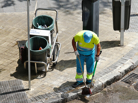 Barrendero barriendo con escoba, recogedor y cubo en calle de Madrid
