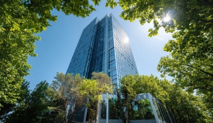 Office tower surrounded by green trees, bright sky