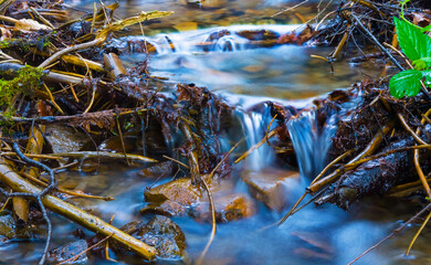small waterfall on mountain brook rushing over a stones