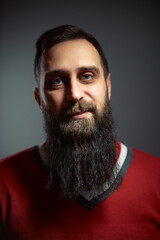 Bearded Man in Red Sweater Smiling Against Dark Background..