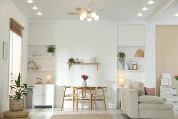Stylish dining table with chairs and comfortable sofa in room. Interior design