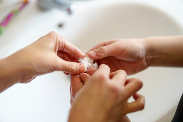 Careful hands performing a delicate task in a bathroom setting during daytime