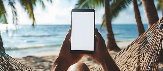 person lying in hammock on tropical beach with smartphone