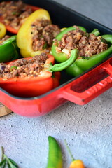 Close-up of Mediterranean-style stuffed bell peppers arranged in a red baking dish, ready for the oven. This homemade meal scene on a light background captures the essence of fresh, flavorful cooking