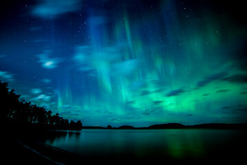 Moon light lake with a dancing northern lights in Farnebofjarden national park in north of Sweden.