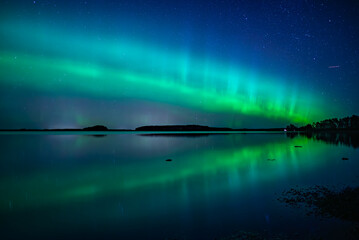 Northern lights dancing over calm lake in north of Sweden.