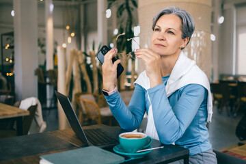 Mature woman with gray hair taking a mindful break during work, coping with menopause and fatigue