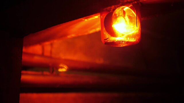 Close-up of a rotating red emergency siren lamp on the wall of a dark tunnel. A bomb shelter, an emergency signal on the wall during an air raid.