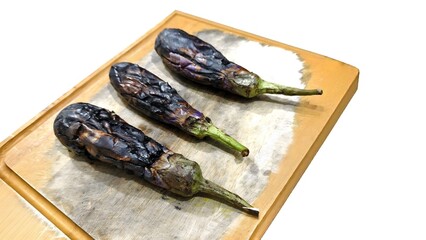 burnt grilled eggplants on wooden cutting board isolated on white background
