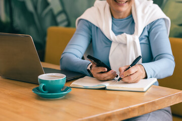 Remote worker mature lady multitasking at cozy cafe