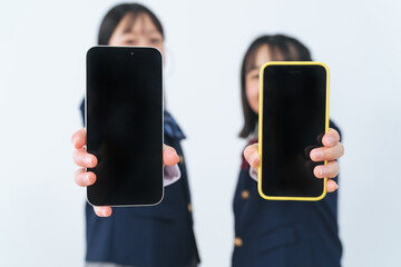スマホの画面を見せる二人の制服の女の子