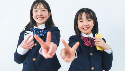 スマホを持ってピースする二人の制服の女の子
