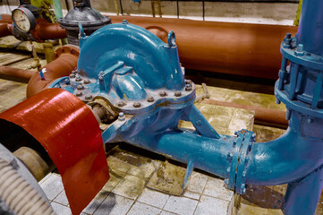 Industrial water pump and piping system in a facility showcasing engineering and maintenance work during daylight hours