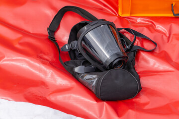 breathing mask with harness straps placed on a red mat. Equipment used by firefighters to protect...