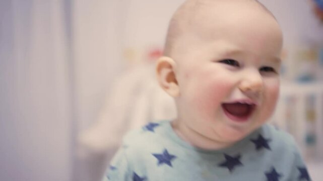 Adorable baby bursts into infectious laughter while lying in comfortable crib, creating priceless family memory of childhood bliss.