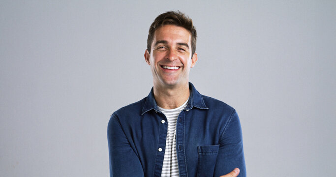 Creative, happy man or portrait with confidence or positive attitude in studio on a gray background. Male person, model or designer with smile in denim jacket for fashion or style on mockup space - Powered by Adobe