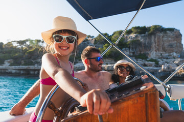 Smiling girl at boat helm with family enjoying sunny day. Summer, vacation, boat concept

