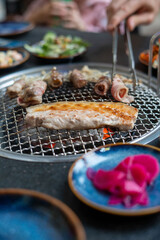 A person is skillfully cutting a large piece of meat on a grill