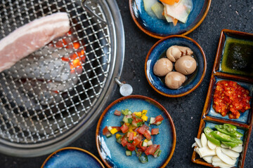 A piece of meat is sizzling on a grill next to appetizing food