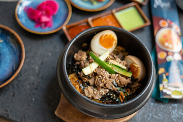 A bowl filled with food, including meat, eggs and vegetables, on a table