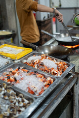 A man is skillfully cooking shrimp in a pan in a vibrant kitchen
