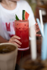 A person is holding a glass of refreshing watermelon juice