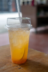 There is a cup of refreshing lemonade with a straw placed on a table