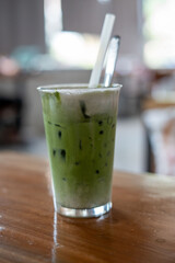 A glass of refreshing green tea with a straw on a table