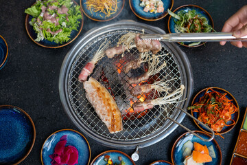 A person is skillfully cooking some meat on a grill with tongs
