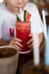 A young child is enjoying a refreshing watermelon drink through a straw