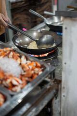A person is diligently cooking food using a frying pan on a stove
