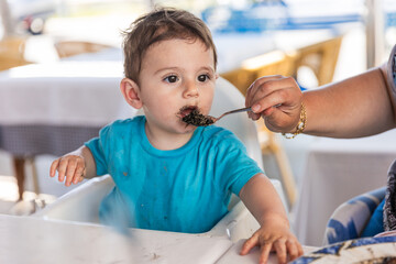 Grandmother feeding one year old grandson with black rice cooked with squid ink