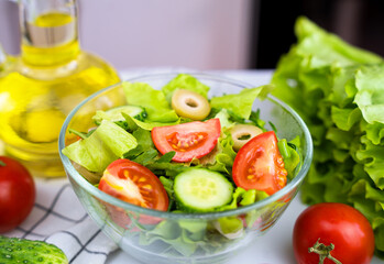 Delicious diet salad of fresh vegetables and greens with olive oil. Healthy food concept. Close-up. Selective focus.