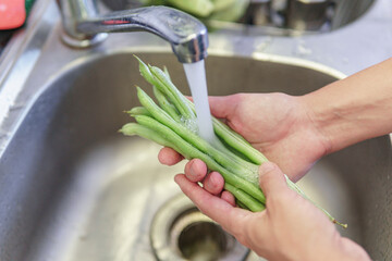 Woman hands washing fresh green beans in a kitchen