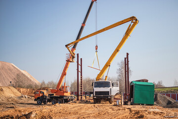 Construction site featuring cranes and machinery working together to lift a heavy load during clear weather
