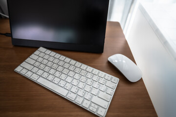 This image captures a serene home office with a minimalist aesthetic. A white keyboard and mouse...