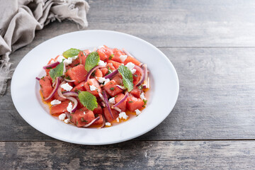 Fresh Watermelon Feta Salad with Mint and Red Onion on wooden table. Copy space