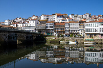 Obraz premium Scenic view from Praza a Enrique Ivntiga Eira Vella, Betanzos, Galicia, with riverside white homes and boats reflecting on the peaceful Mandeo River.