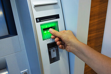 A person inserts a bank card into an ATM slot, initiating a secure banking transaction. Closeup of...