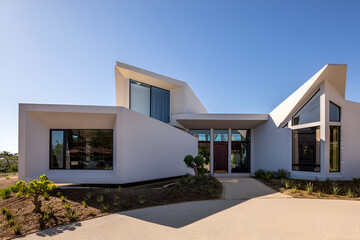 Modern white house with geometric design and clear blue sky