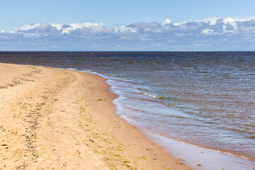 Calm sandy shoreline with soft waves lapping onto the coast