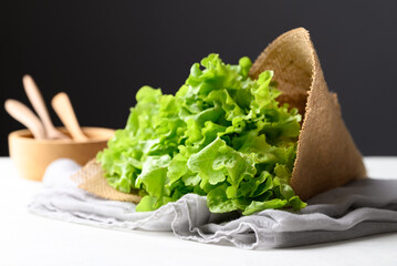 Organic green oak lettuce wrapped by burlap on fabric with white table, Fresh vegetable