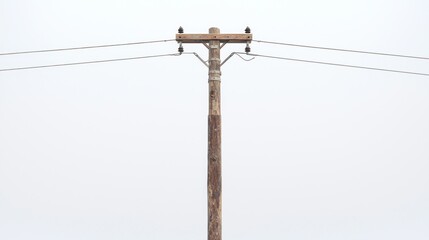 Aged wooden pole with wires against a blurred sky