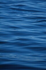 Naklejka premium Close-up view of smooth blue ocean water surface with gentle ripples reflecting sunlight