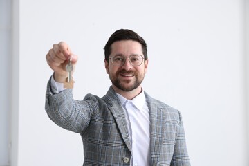 Real estate agent holding key with house shaped keychain indoors