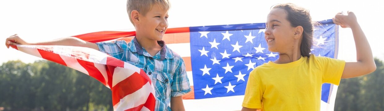 Children sit with American flag outdoors.
