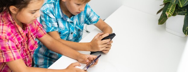 Education, friendship, technology and people concept. children using mobile phone, pointing fingers, while sitting 