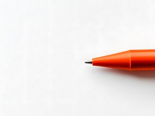 A close up shot of an orange pen with a silver tip on a white surface in a well lit environment space