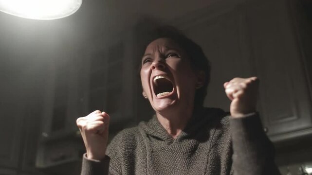 Woman Expressing Intense Frustration and Anger in a Dimly Lit Kitchen Setting