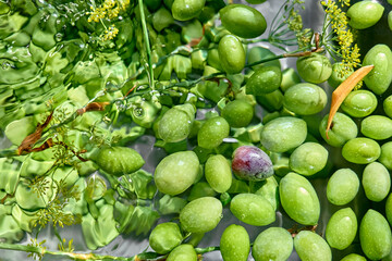 Green olives floating in water with splashes and water drops.